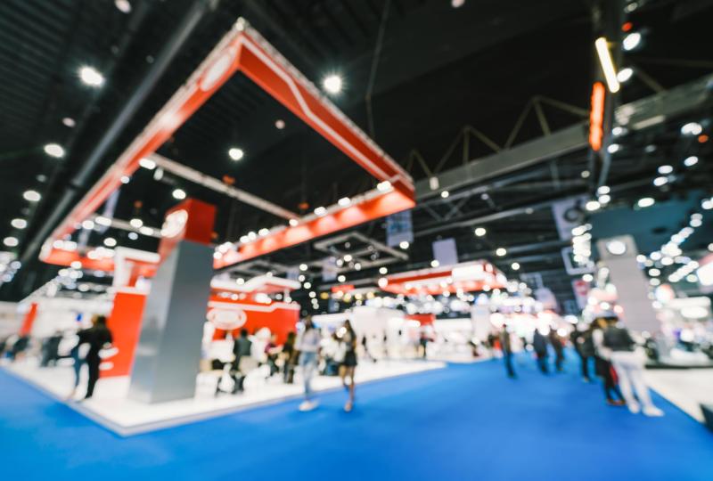 Fiera vivace, luci brillanti e folla in movimento su tappeto blu.